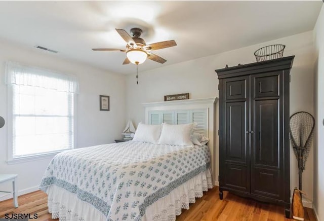 bedroom featuring light wood-style floors, visible vents, baseboards, and a ceiling fan