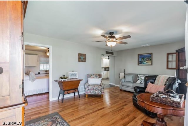 living room with visible vents, ceiling fan, and light wood finished floors