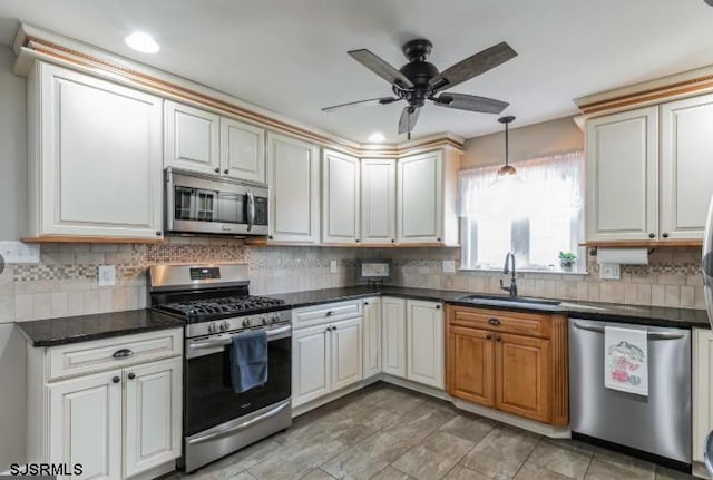 kitchen featuring dark countertops, ceiling fan, a sink, stainless steel appliances, and backsplash