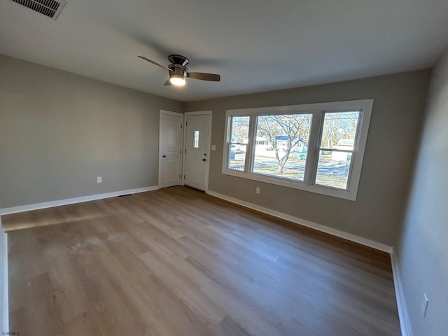 unfurnished room with visible vents, ceiling fan, baseboards, and wood finished floors