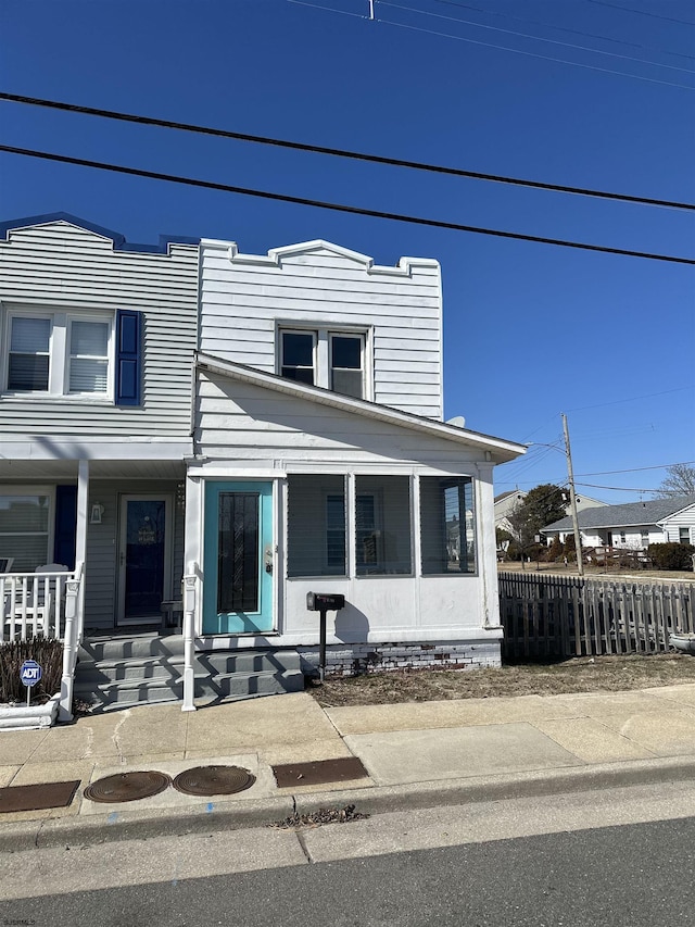 view of front of property with fence and a sunroom