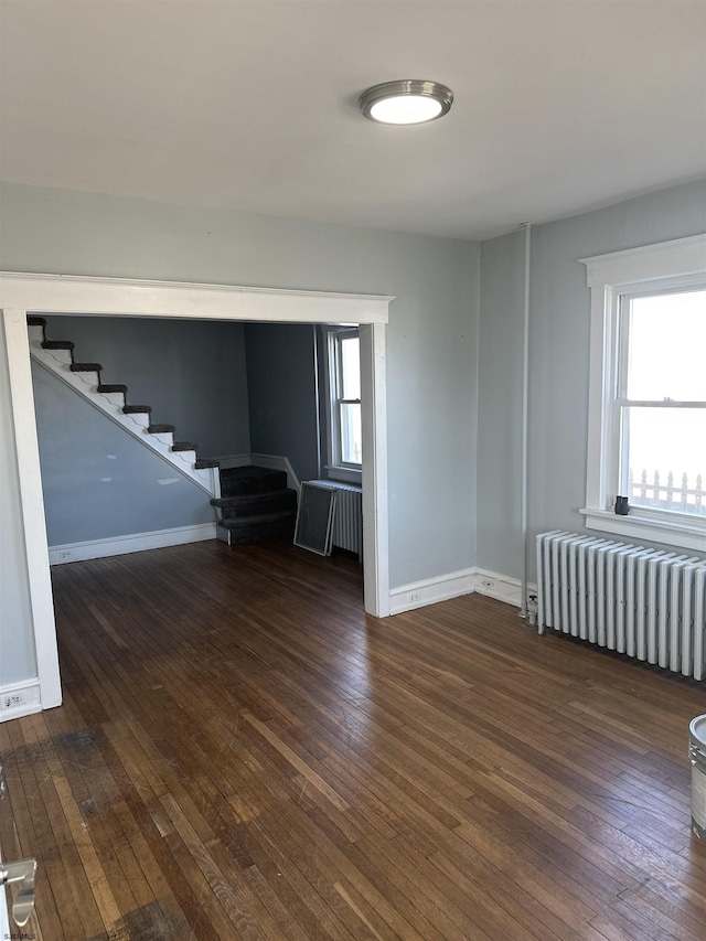 empty room featuring hardwood / wood-style floors, stairway, and radiator