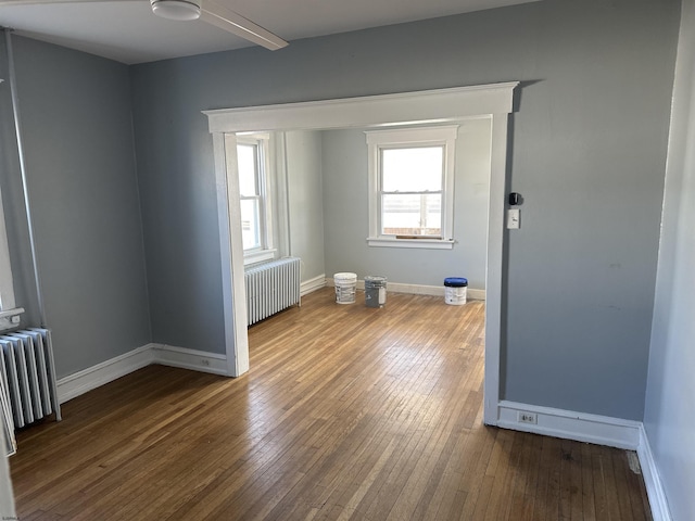 spare room with radiator, wood-type flooring, and baseboards