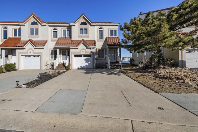 view of front of property featuring a tiled roof, concrete driveway, and stucco siding