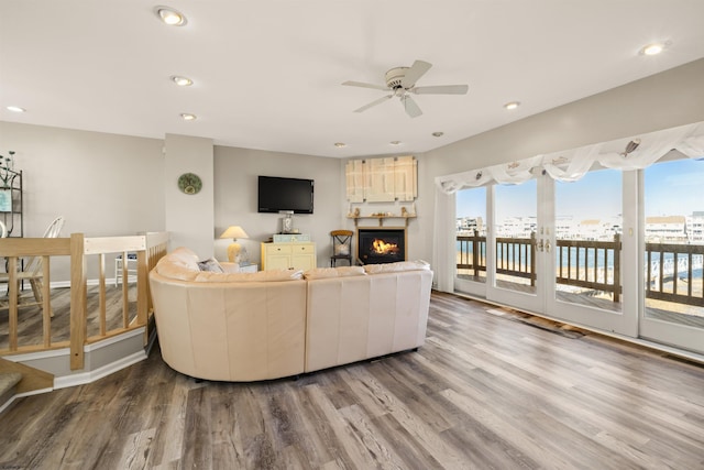 living room featuring visible vents, ceiling fan, wood finished floors, a lit fireplace, and recessed lighting