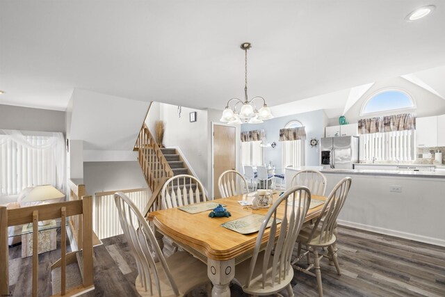 dining area with lofted ceiling, stairway, a chandelier, and dark wood-type flooring