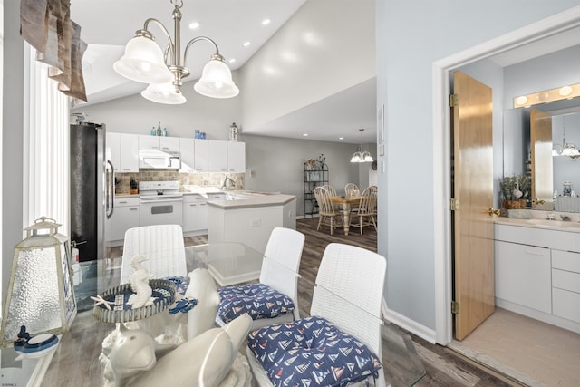 dining space featuring recessed lighting, wood finished floors, a towering ceiling, and an inviting chandelier