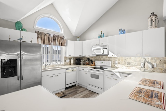 kitchen featuring lofted ceiling, white appliances, decorative backsplash, and a sink