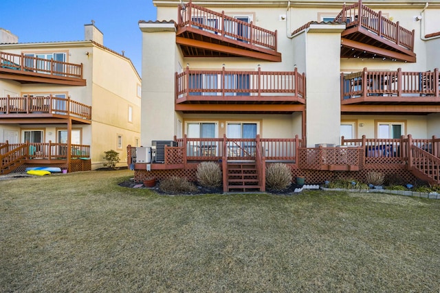 back of property featuring a lawn and stucco siding