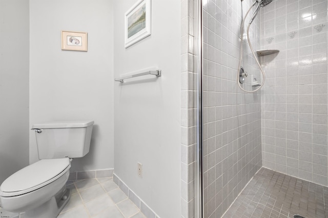 full bathroom featuring baseboards, a tile shower, toilet, and tile patterned floors