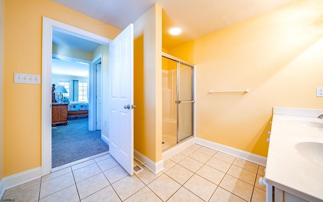 ensuite bathroom featuring tile patterned flooring, baseboards, a sink, and a shower stall