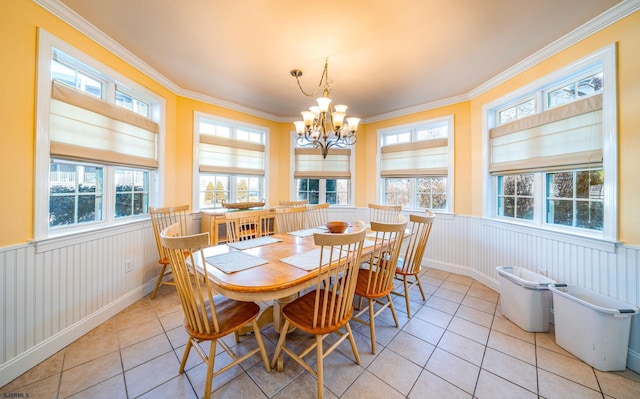 dining space featuring an inviting chandelier, light tile patterned floors, ornamental molding, and wainscoting