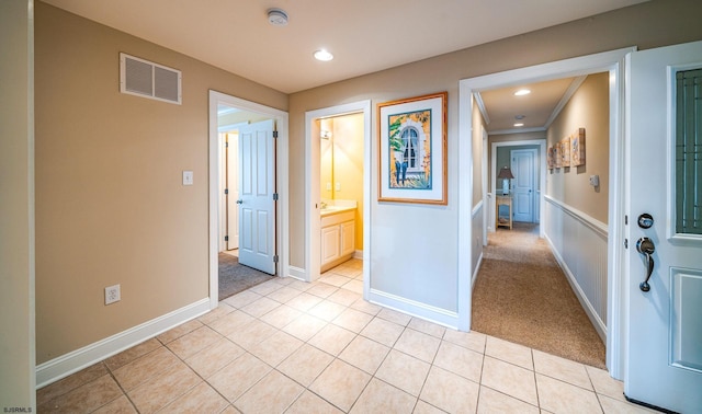 corridor featuring light tile patterned floors, recessed lighting, visible vents, light carpet, and baseboards