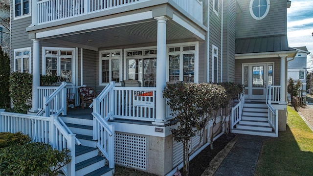 view of exterior entry with a porch, a standing seam roof, and metal roof