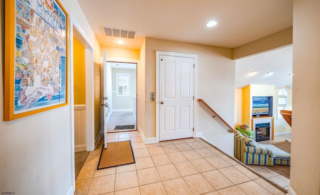 foyer entrance with light tile patterned floors, baseboards, a fireplace, and visible vents