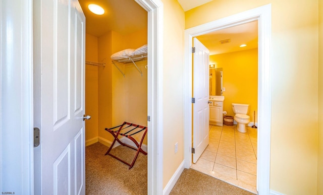 corridor with baseboards and light tile patterned flooring