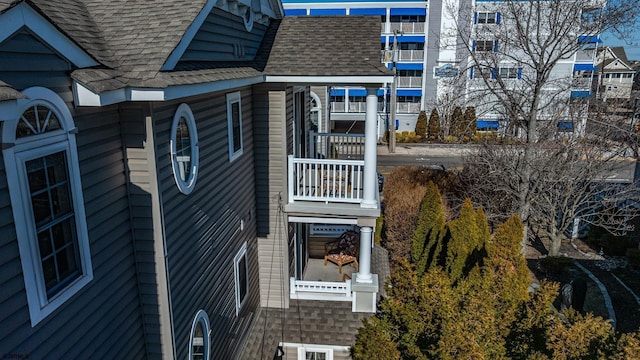 view of property exterior featuring a balcony and a shingled roof