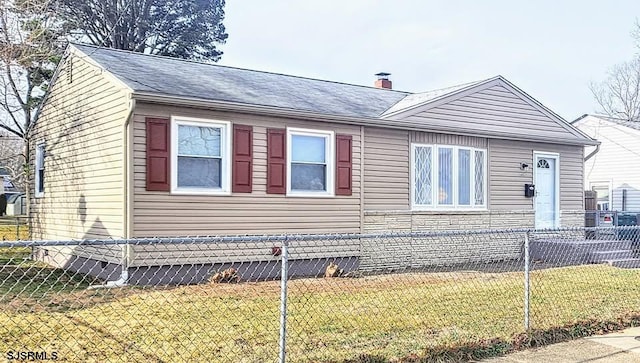 view of side of home with stone siding, a lawn, a chimney, and a fenced front yard