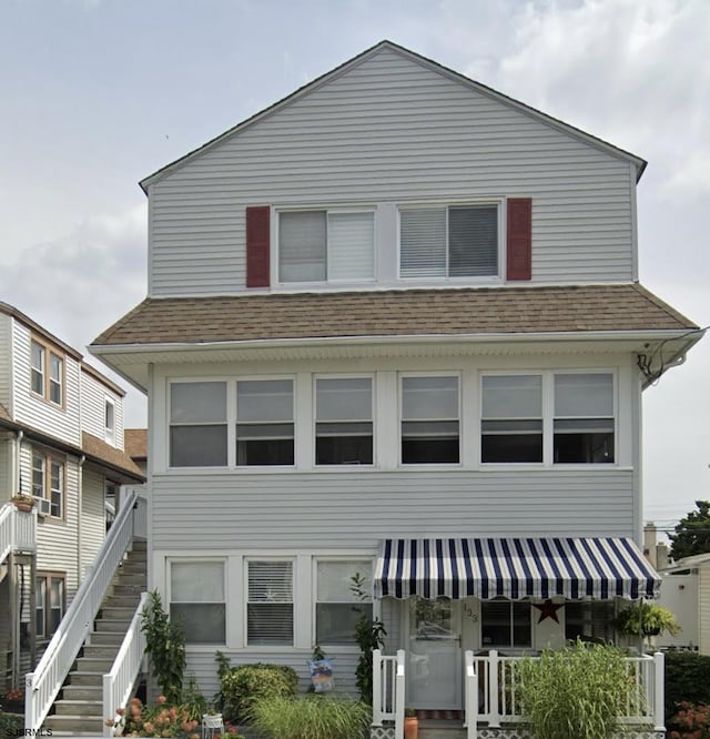 view of front of home with roof with shingles and stairway