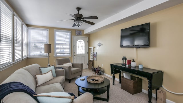 living area with a wealth of natural light, ceiling fan, baseboards, and carpet flooring