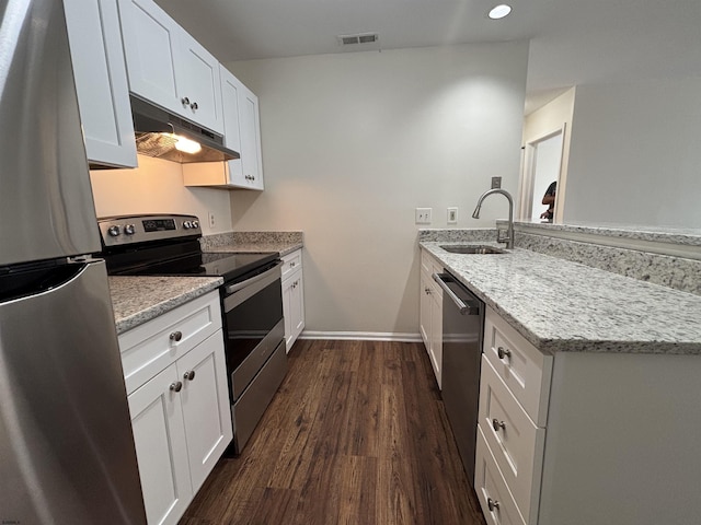 kitchen with under cabinet range hood, a peninsula, dark wood-type flooring, visible vents, and appliances with stainless steel finishes