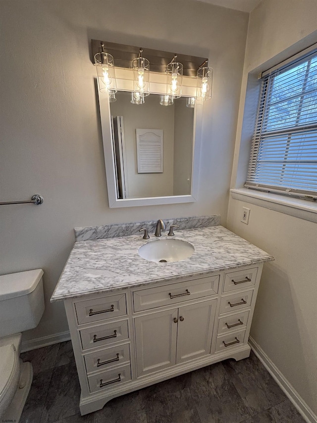 bathroom featuring baseboards, vanity, and toilet