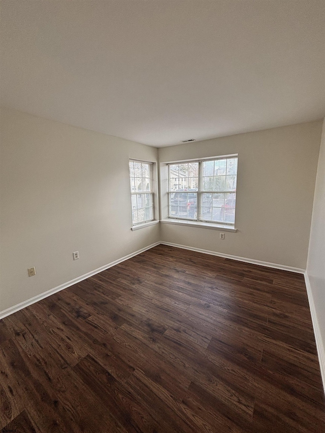 spare room with dark wood-style floors and baseboards