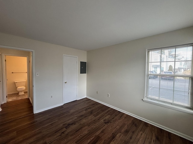 unfurnished bedroom featuring dark wood-style flooring, electric panel, and baseboards