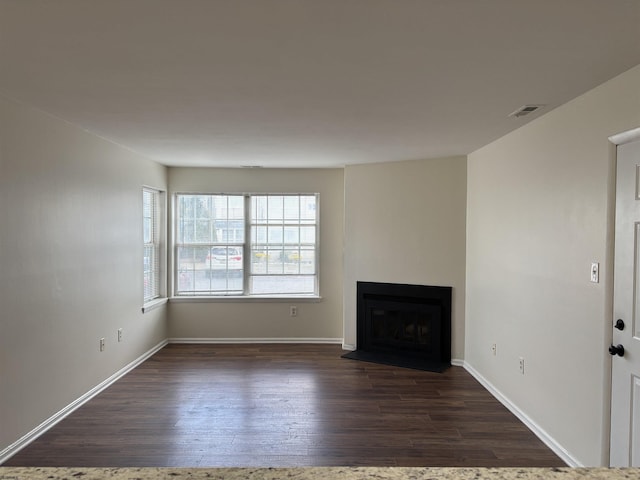 unfurnished living room featuring dark wood-style floors, a fireplace, visible vents, and baseboards