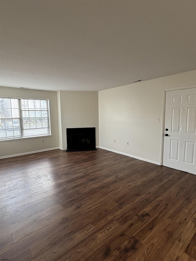 unfurnished living room featuring baseboards, a fireplace, visible vents, and dark wood-style flooring