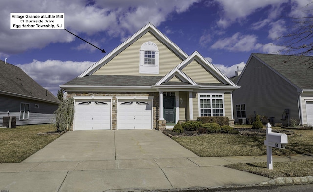 view of front of property featuring stone siding, concrete driveway, central AC, and an attached garage