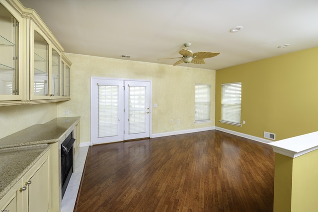 kitchen featuring baseboards, ceiling fan, visible vents, and dark wood-style flooring