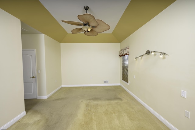 carpeted empty room with visible vents, baseboards, vaulted ceiling, and a ceiling fan