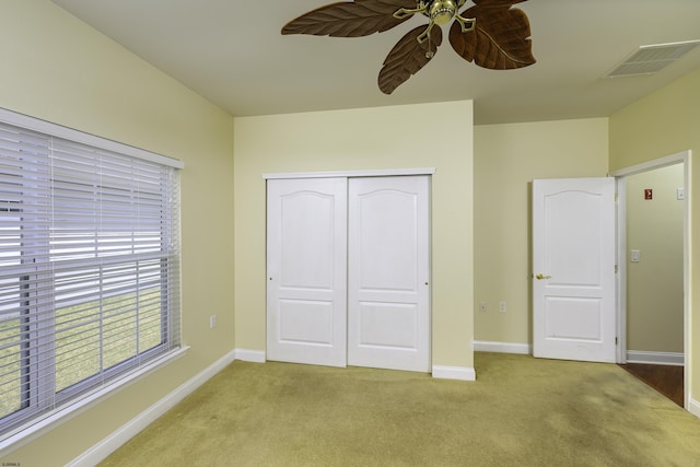 unfurnished bedroom with a closet, light colored carpet, visible vents, a ceiling fan, and baseboards