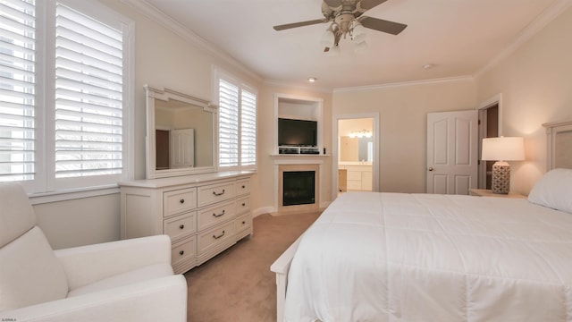 bedroom featuring light colored carpet, ceiling fan, ornamental molding, ensuite bathroom, and a fireplace