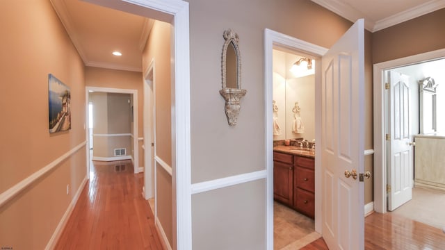 hallway featuring crown molding, recessed lighting, visible vents, light wood-style flooring, and baseboards