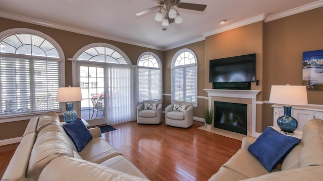 living room featuring a fireplace with flush hearth, a healthy amount of sunlight, wood finished floors, and crown molding