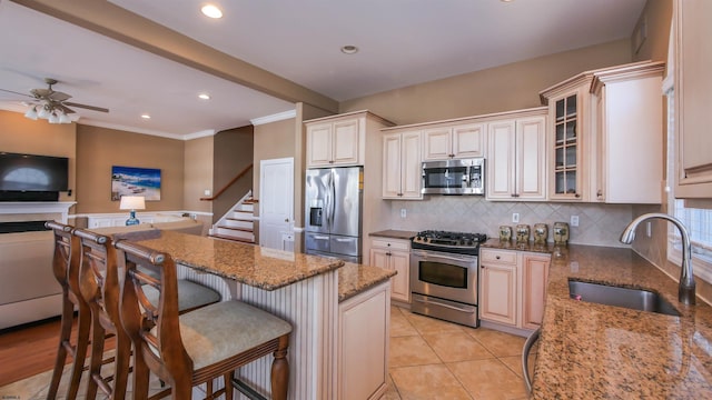 kitchen featuring light stone counters, stainless steel appliances, a sink, tasteful backsplash, and glass insert cabinets