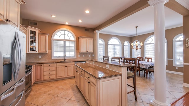 kitchen featuring stainless steel appliances, a sink, visible vents, a kitchen bar, and ornate columns