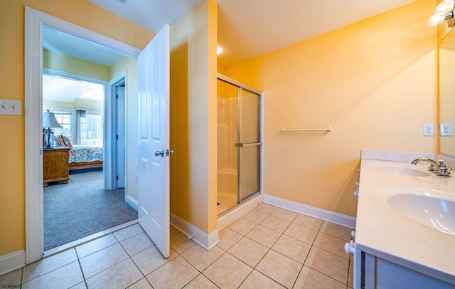 ensuite bathroom featuring a stall shower, baseboards, ensuite bath, tile patterned floors, and a sink