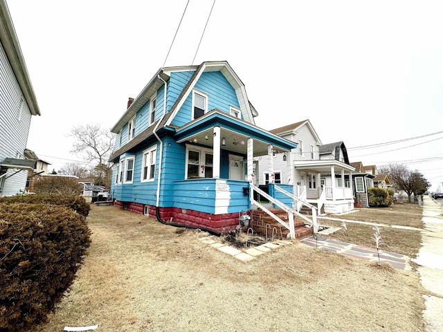 dutch colonial with covered porch, a chimney, and a gambrel roof