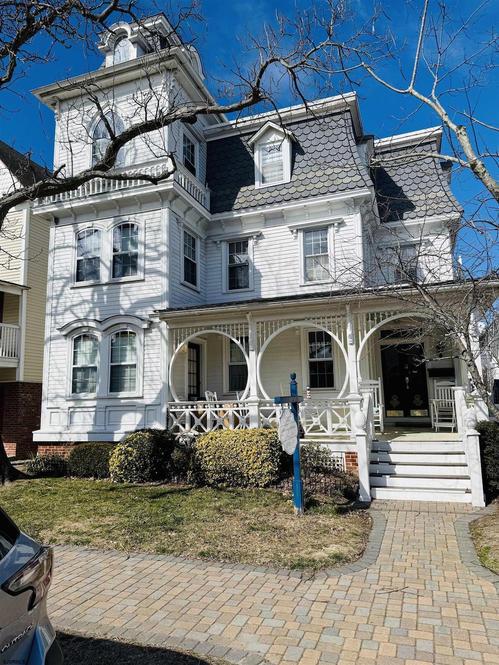 victorian home with covered porch and mansard roof