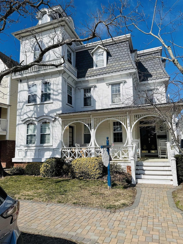 victorian home with covered porch and mansard roof