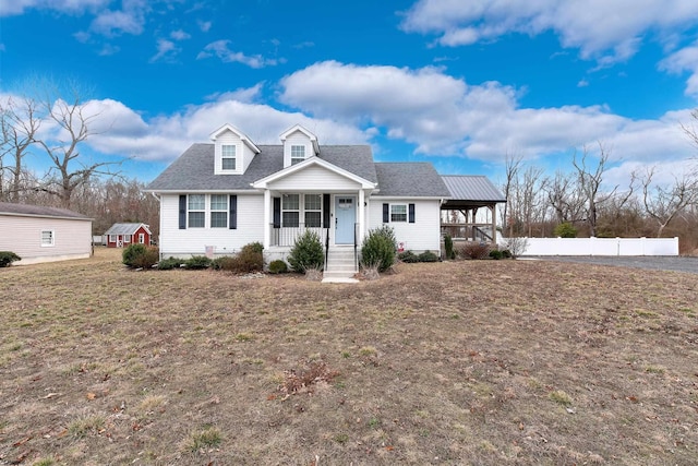 cape cod-style house featuring covered porch, a front lawn, roof with shingles, and fence