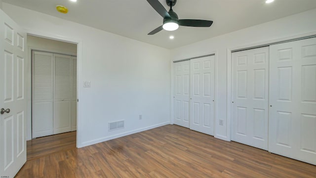 unfurnished bedroom with baseboards, visible vents, wood finished floors, multiple closets, and recessed lighting