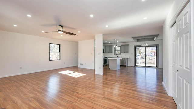 unfurnished living room with light wood-style floors, baseboards, a ceiling fan, and recessed lighting