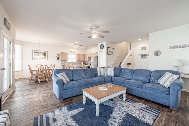 living room featuring baseboards, ceiling fan, stairway, and wood finished floors