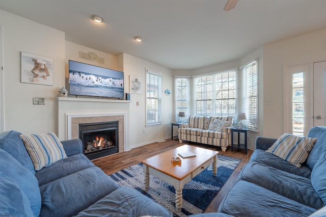 living room featuring baseboards, wood finished floors, and a tile fireplace