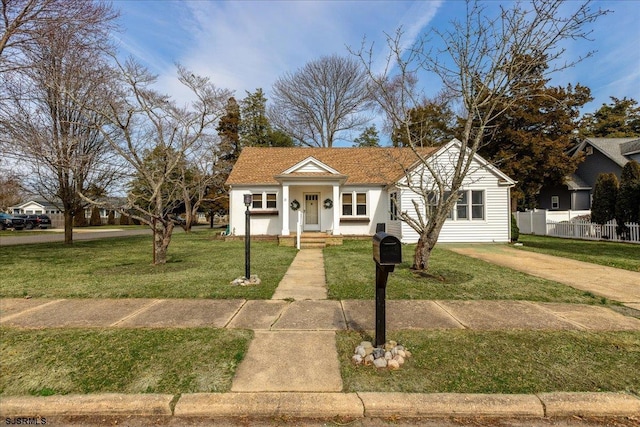 bungalow-style home featuring a front lawn and fence