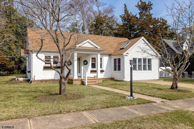 bungalow-style home featuring fence, a front yard, and a shingled roof